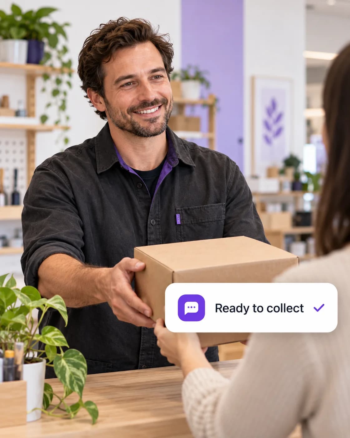 A parcel marked ready to collect being handed across a workshop counter